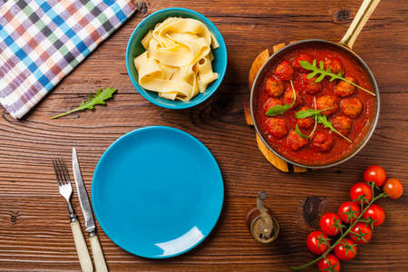 Italian pasta pappardelle with meatballs in tomato sauce, sprinkled with cheese and arugula. Top view.の写真素材