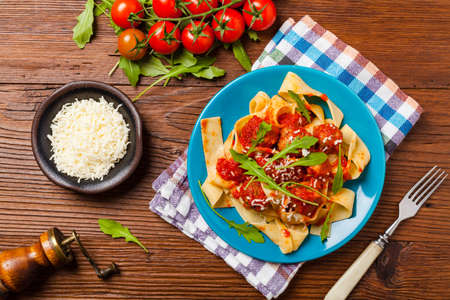 Italian pasta pappardelle with meatballs in tomato sauce, sprinkled with cheese and arugula. Top view.の写真素材