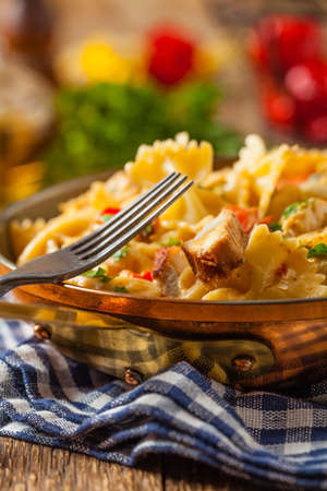 Pasta farfalle with chicken and paprika, in carbonara sauce, served in an old copper pan.  Front view.の写真素材