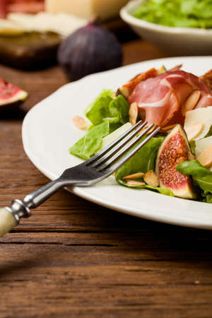 Fresh salad with figs and prosciutto with parmesan cheese and toasted almonds. Front view.の写真素材