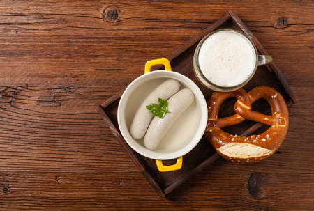 Boiled white sausages, served with beer and pretzels. Perfect for Octoberfest. Natural wooden background. Top view.の写真素材