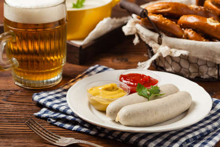 Boiled white sausages, served with beer and pretzels. Perfect for Octoberfest. Natural wooden background. Front view.の写真素材