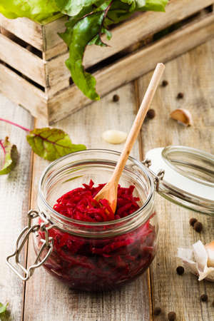 Grated beetroot marinated in jars. Wooden background.の写真素材