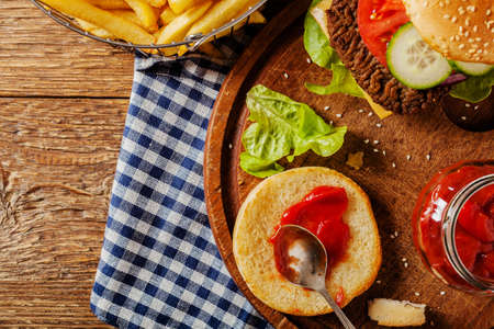 Homemade, beef hamburger with cheese and vegetables. Served with French fries. Top view.の写真素材