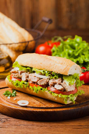 Delicious tuna sandwich, served with lettuce, tomato and onion. Natural wood in the background. Front view.の写真素材