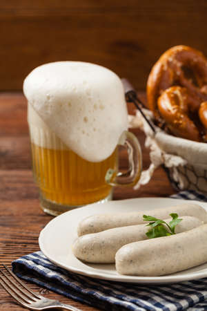 Boiled white sausages, served with beer and pretzels. Perfect for Octoberfest. Natural wooden background. Front view.の写真素材
