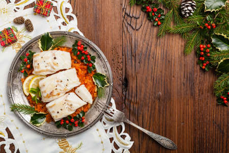 Christmas fish. Roasted cod pieces, served in vegetable sauce. Xmas styling. Top view.