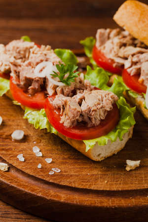 Delicious tuna sandwich, served with lettuce, tomato and onion. Natural wood in the background. Front view.の写真素材