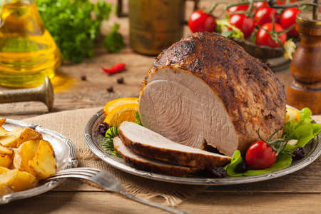 Baked ham, served on an old plate. Natural wooden background. Front view.の写真素材