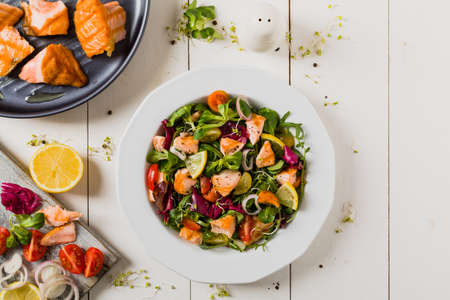 Delicious salad with pieces of grilled salmon. Top view. White wooden background.の写真素材