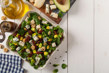Italian salad with avocado, gorgonzola cheese, pistachio nuts, sun-dried tomatoes and croutons. Top view. White woodem background. の写真素材