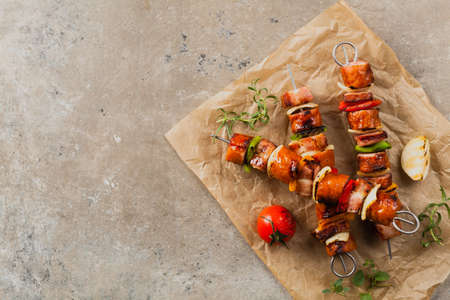 Grilled skewers with sausage, bacon and vegetables. Top view. stone background. の写真素材