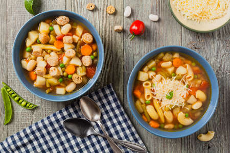 Minestrone soup with pasta and cheese or crostini. Natural wooden background. Top view.の写真素材