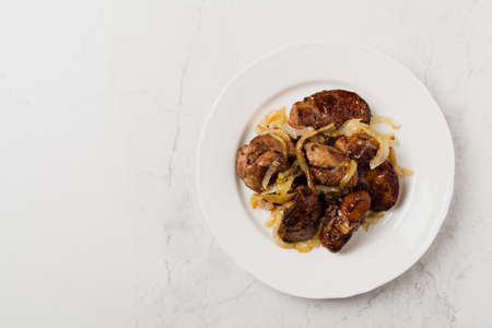 Fried chicken liver with onions. Top view. Stone background.の写真素材