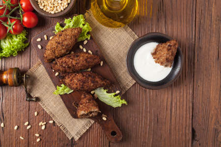 Traditional arabic kibbeh with lamb and pine nuts. Top view. Natural wooden background.