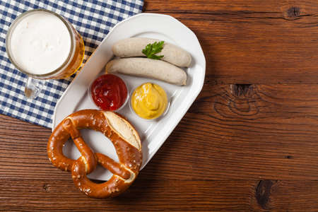 Boiled white sausages, served with beer and pretzels. Perfect for Octoberfest. Natural wooden background. Top view.の写真素材