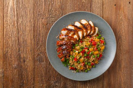 Grilled chicken breast in teriyaki sauce. Served with brown rice and vegetables. Top view. Flat lay.の写真素材