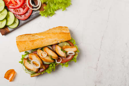 Chicken sandwich with tomato, cucumber, lettuce and onions. White stone background. Top view. Flat lay.の写真素材