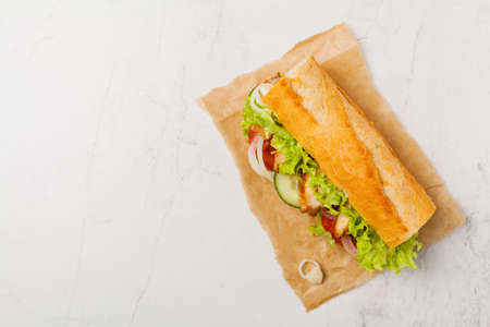Chicken sandwich with tomato, cucumber, lettuce and onions. White stone background. Top view. Flat lay.の写真素材