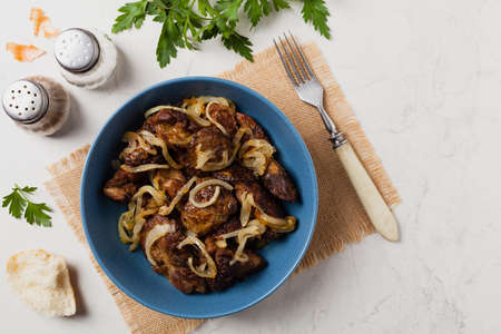 Fried chicken liver with onions. Top view. Stone background.の写真素材