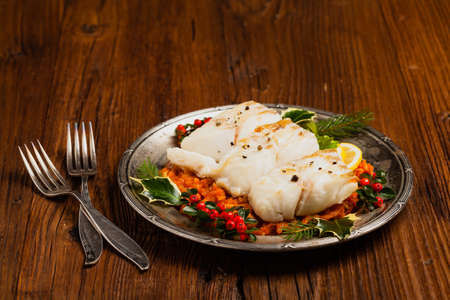 Christmas fish. Roasted cod pieces, served in vegetable sauce. Xmas styling. Front view.の写真素材