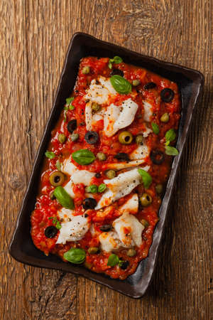 Cod in Italian in tomatoes with olives and capers. Top view.の写真素材