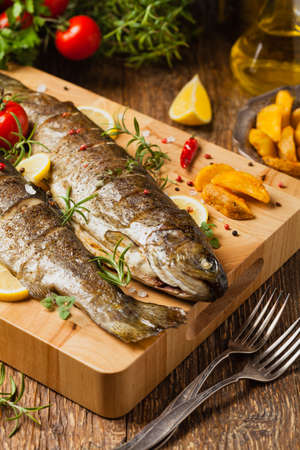 Grilled whole trout. Served with baked potatoes. Front view.