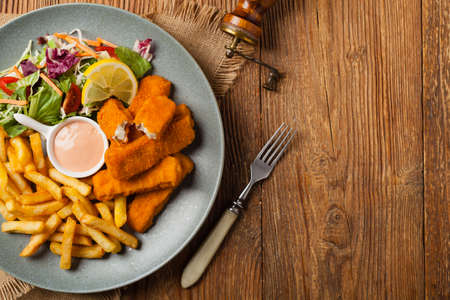Fish sticks with fries and salad on grey plate. Top view.の写真素材