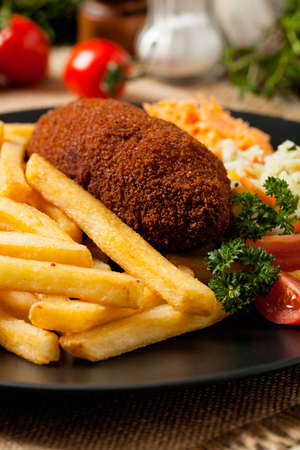 Chicken Kiev (de Volaille chop) with french fries and salads. Front view.