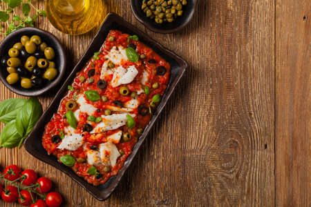 Cod in Italian in tomatoes with olives and capers. Top view.の写真素材