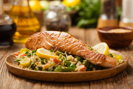 Asian dish. Fried salmon with rice and vegetables. Sprinkled with sesame seeds. Front view. Natural background.の写真素材