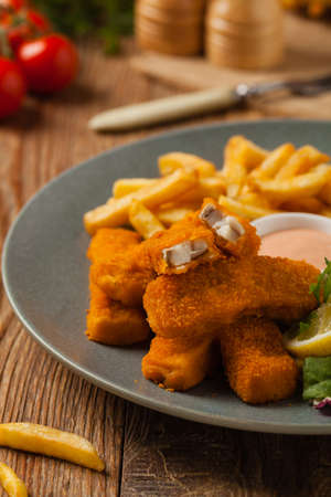 Fish sticks with fries and salad on grey plate. Front view.の写真素材