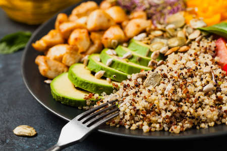 Salad with quinoa, avocado and chicken. Front view. Served on a black plate.の写真素材