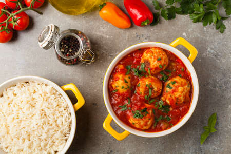 Chicken meatballs with tomato sauce. Served with rice. Top view. Stone background.