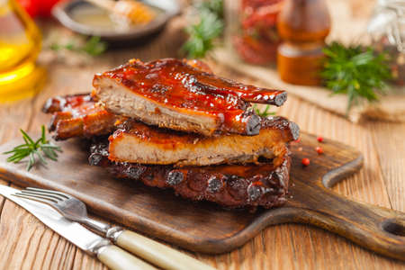 Roasted pork ribs in a bbq sauce. Served on a wooden board. Front view.の写真素材