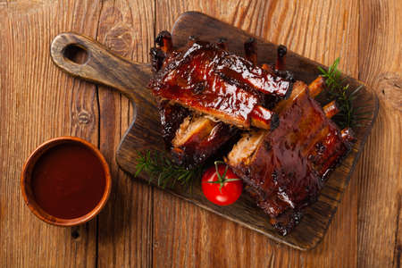 Roasted pork ribs in a bbq sauce. Served on a wooden board. Top view.の写真素材
