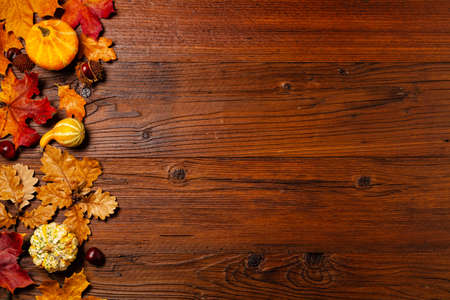 Wooden background. Arranged autumn leaves and pumpkins. Top view.の写真素材
