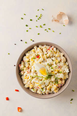 A light egg salad with celery, gherkin, pepper and mayonnaise. Served in a bowl on a light background. Top view.の写真素材
