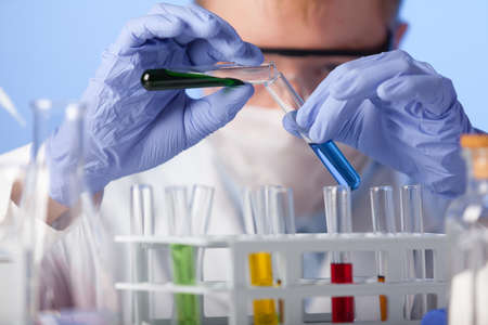 Lab. A lab technician in a white coat and rubber gloves and protective glasses is investigating the...
