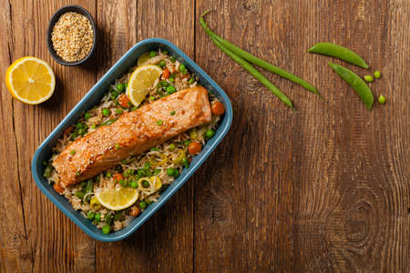 Asian dish. Fried salmon with rice and vegetables. Sprinkled with sesame seeds. Top view. Natural background. の写真素材