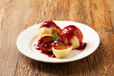 Dumplings with plums, topped with plum sauce or served with cream and sugar. Front view.の写真素材