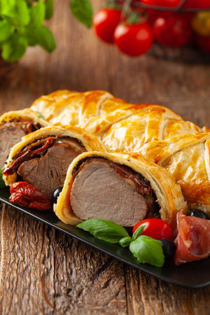 Baked sirloin in puff pastry. Sliced pieces, served with sun-dried tomatoes, salad, and olives.の写真素材
