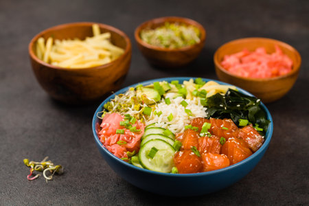 Hawaiian salmon poke bowl with seaweed, avocado, sesame seeds. Front view. Black background.