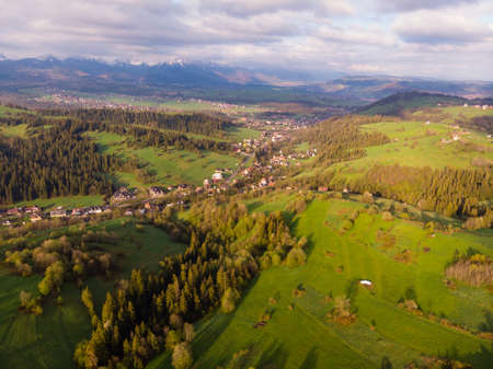 View from above on beautiful green meadows, snow-capped peaks of the Tatra Mountains in the...