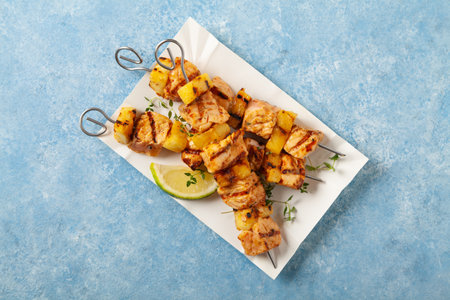 Grilled shashlik with salmon and pineapple. Served on paper try. Blue painted background.の写真素材