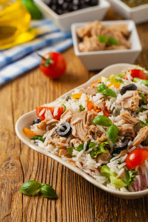 Italian tuna salad with rice, olives and capers. Front view. Natural wooden background.の写真素材