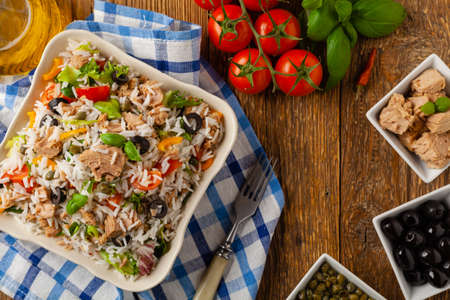 Italian tuna salad with rice, olives and capers. Top view. Natural wooden background.の写真素材