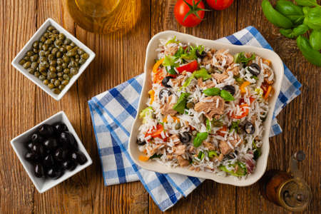 Italian tuna salad with rice, olives and capers. Top view. Natural wooden background.の写真素材