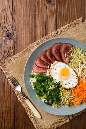 Korean beef with sprouts, spinach and fried egg. Top view.の写真素材