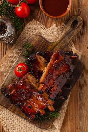 Roasted pork ribs in a bbq sauce. Served on a wooden board. Top view.の写真素材